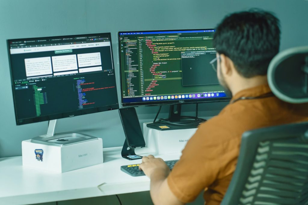 Developer reviewing project code on two monitors