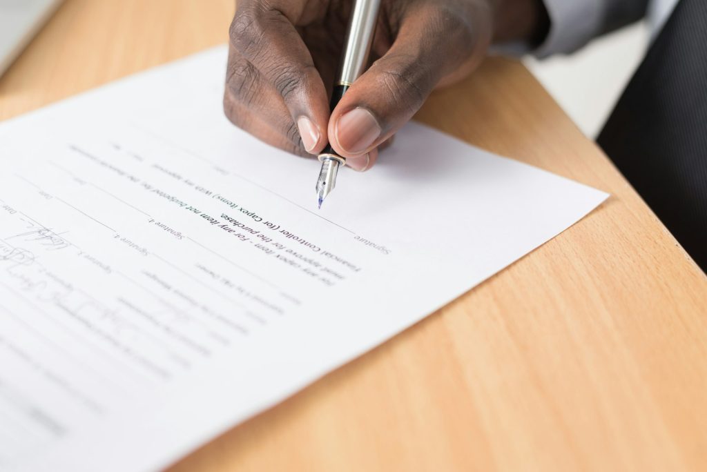 Hand signing a written agreement with a pen
