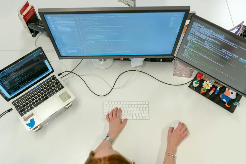 Software testing desk with a laptop and two monitors, set up the way QA teams in Pune work