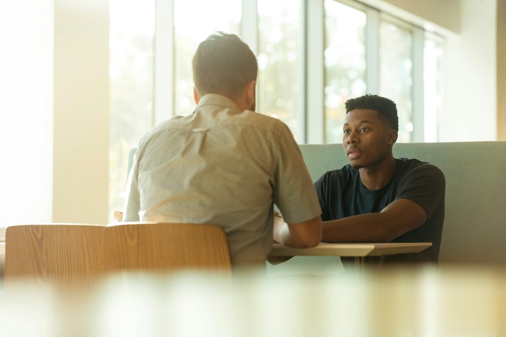 Candidate in a technical interview across a table, seen from behind